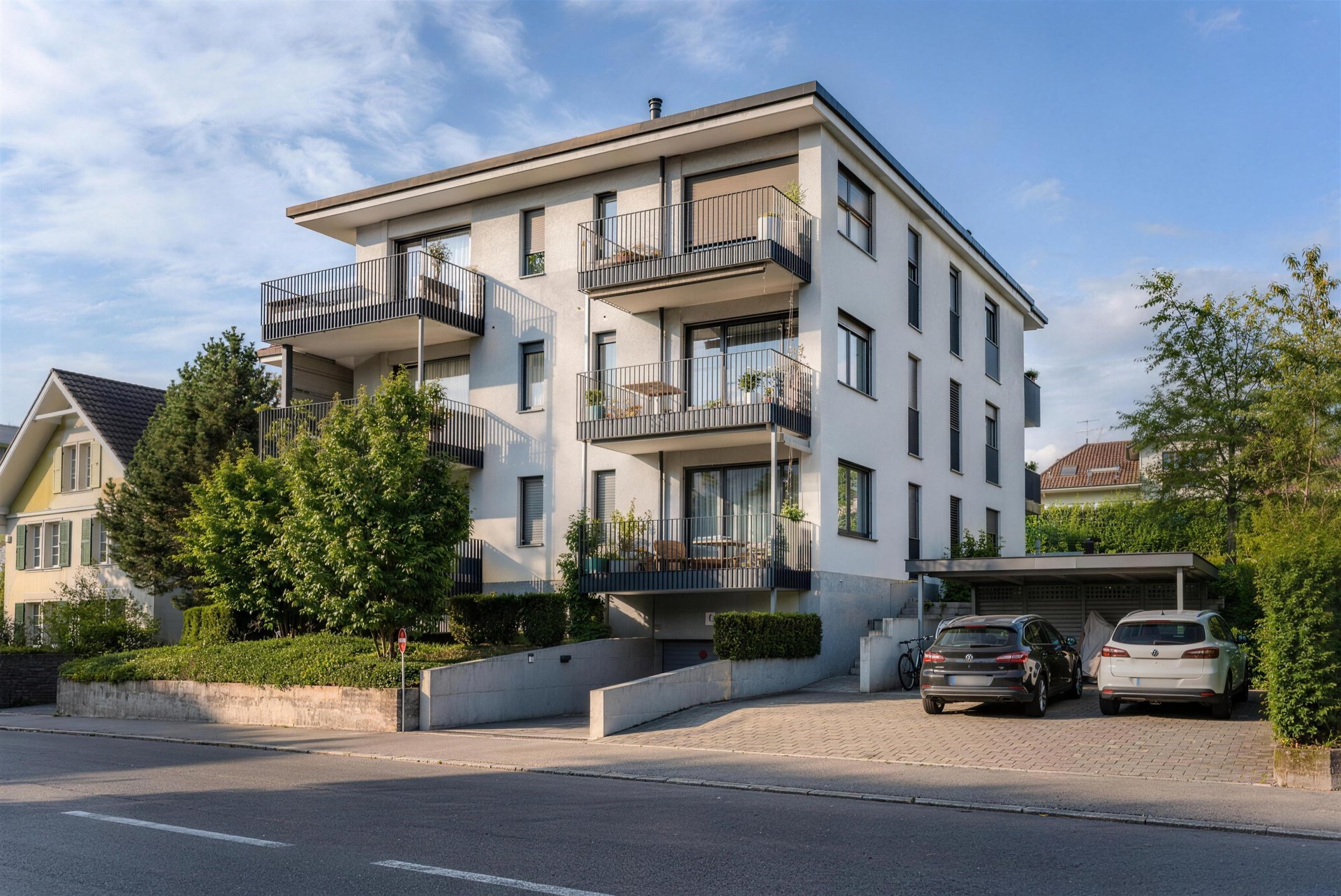 Modernes Mehrfamilienhaus mit Balkonen an sonniger Quartierstrasse